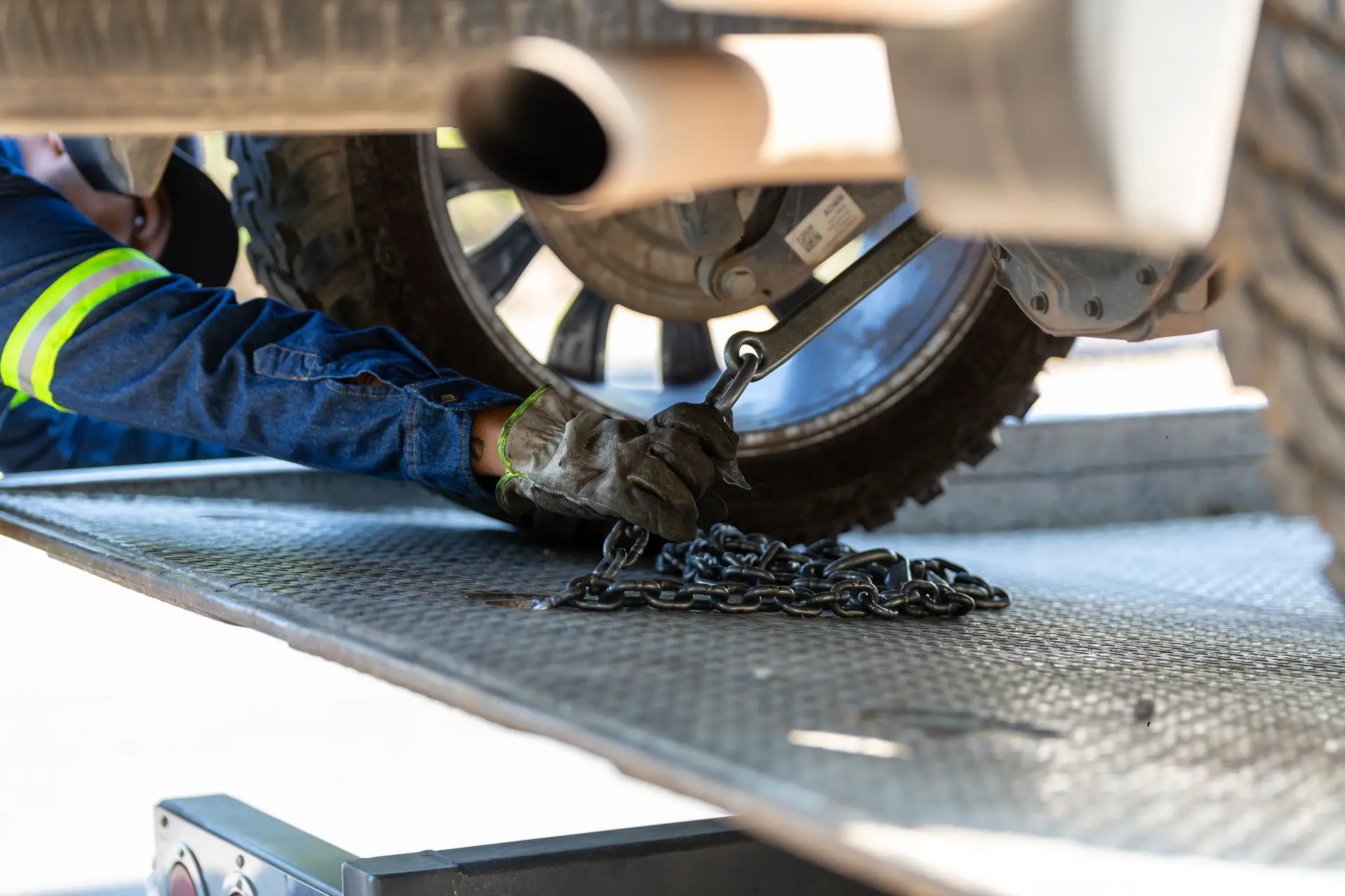 Tow operator securing a vehicle to a flatbed with a wheel chain